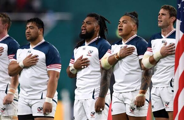Rugby coach explaining a training drill to players on the field