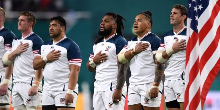 Rugby coach explaining a training drill to players on the field