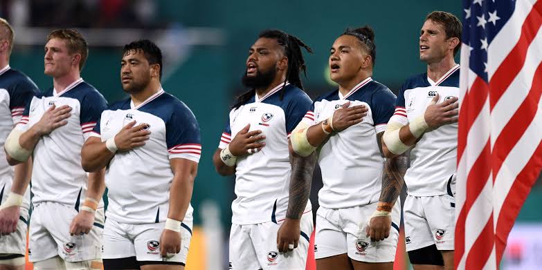 Rugby coach explaining a training drill to players on the field